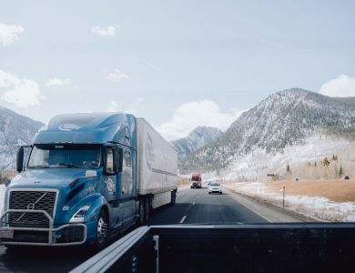 a blue semi truck driving down a mountain road