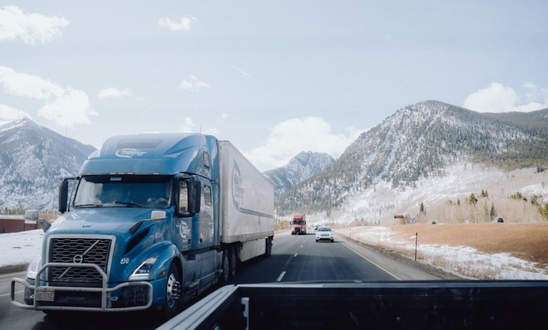 a blue semi truck driving down a mountain road