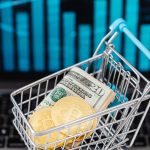 Symbolic image of cryptocurrency and cash in a shopping cart on a laptop, representing digital finance and trading.