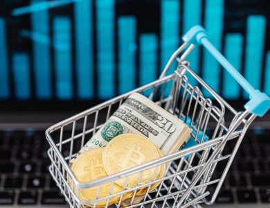 Symbolic image of cryptocurrency and cash in a shopping cart on a laptop, representing digital finance and trading.