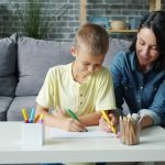 Mother and son drawing together at a table.