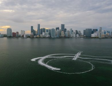 Aerial shot of Miami's skyline with watercraft patterns on the ocean surface.