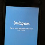 Close-up of a smartphone displaying the Instagram app welcome screen, inviting users to sign up.