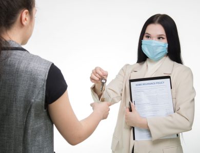 Real estate agent in a face mask hands keys to a client, illustrating safe business practices.