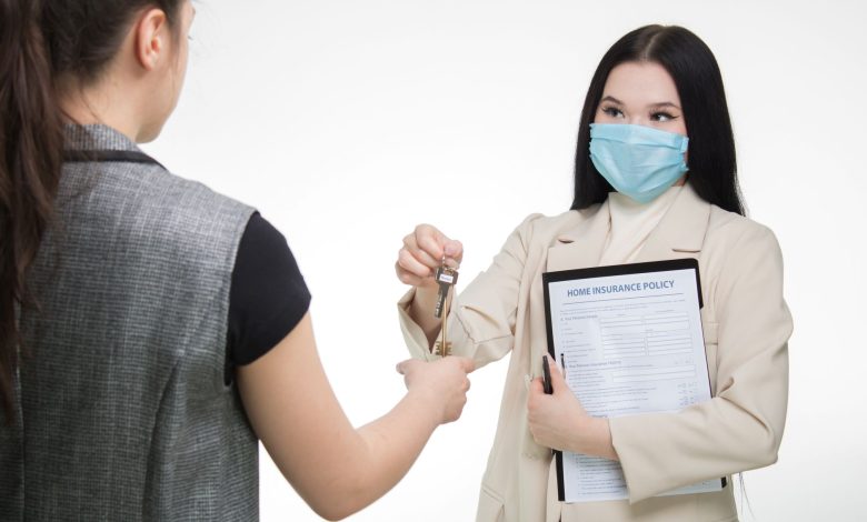 Real estate agent in a face mask hands keys to a client, illustrating safe business practices.