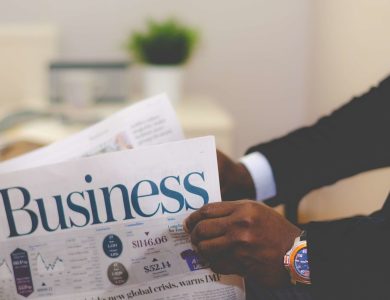 Close-up of a businessman reading a newspaper indoors, focusing on business headlines.