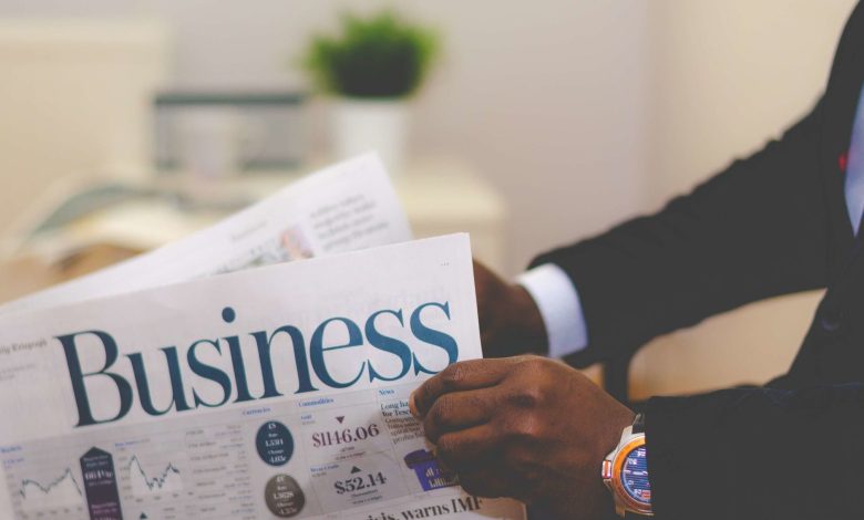 Close-up of a businessman reading a newspaper indoors, focusing on business headlines.