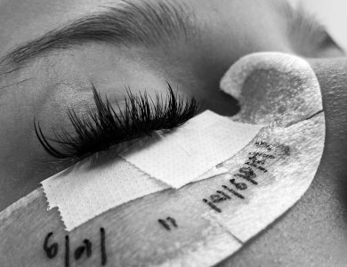 Detailed black and white image of eyelash extension procedure close-up.