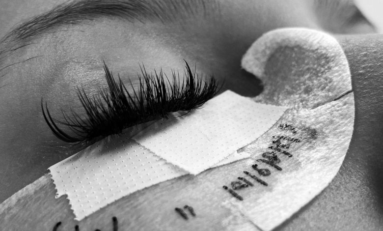 Detailed black and white image of eyelash extension procedure close-up.
