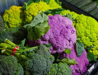 Colorful assortment of fresh broccoli and purple cauliflower at a market. Perfect for healthy food concepts.
