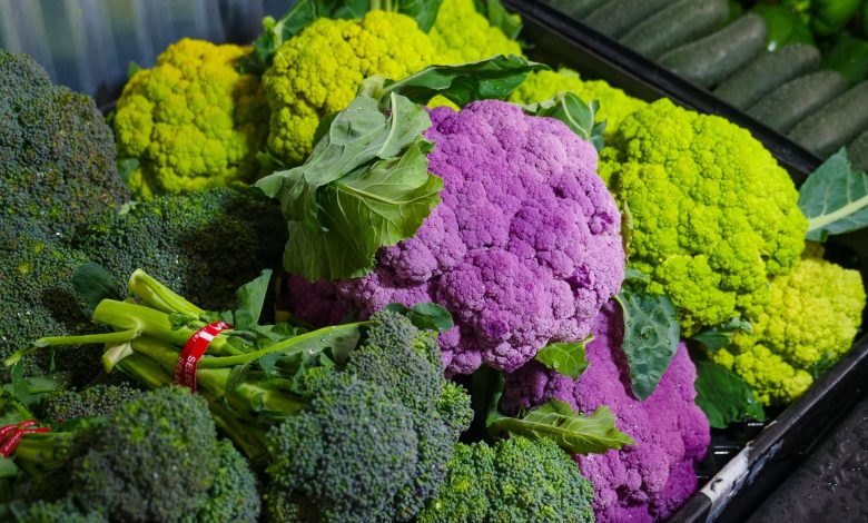 Colorful assortment of fresh broccoli and purple cauliflower at a market. Perfect for healthy food concepts.