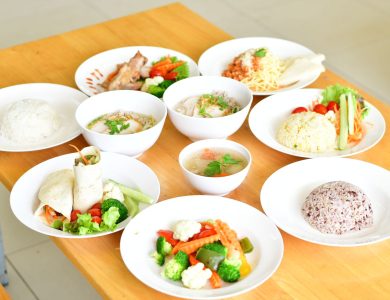 A variety of healthy dishes including rice, soup, and vegetables served on a wooden table.