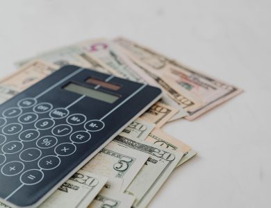 A close-up of a calculator and US dollar banknotes, symbolizing financial calculation and budgeting.