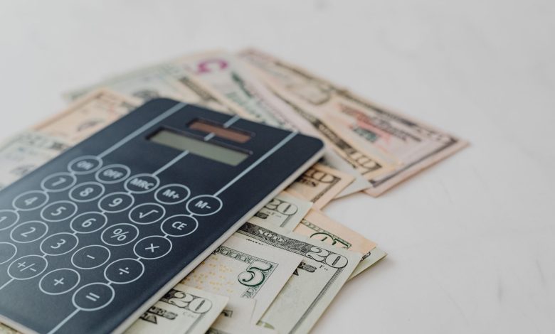 A close-up of a calculator and US dollar banknotes, symbolizing financial calculation and budgeting.