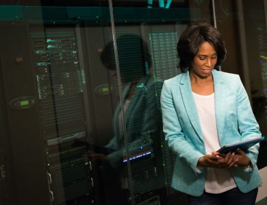 Female IT professional examining data servers in a modern data center setting.
