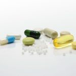 Close-up of various pills and capsules on a white surface, representing healthcare.