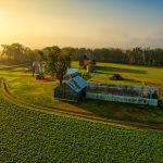 Stunning aerial photo of a rural farm in Minnesota, showcasing lush fields and historic barns at sunrise.