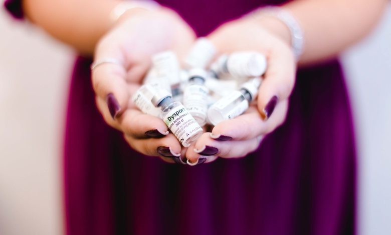 Close-up of a woman's hands holding multiple medical vials, emphasizing healthcare and cosmetic treatment.