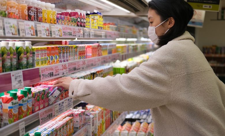 Masked woman shopping for beverages in a supermarket aisle