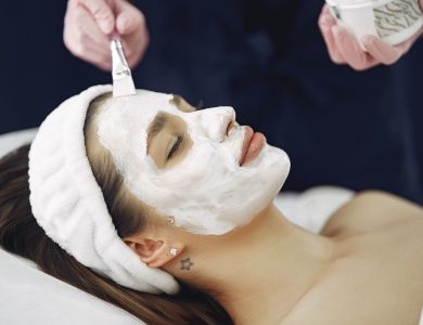 Close-up of a woman with eyes closed enjoying a calming facial mask application at a spa.