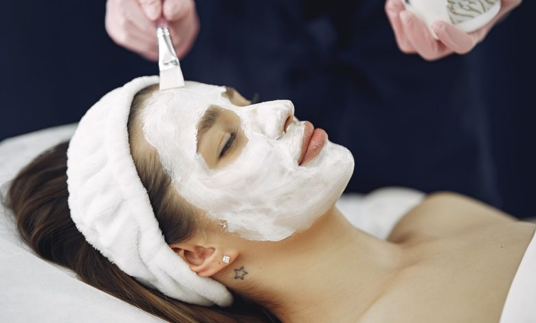 Close-up of a woman with eyes closed enjoying a calming facial mask application at a spa.
