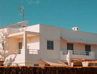 Elegant modern white house with balconies under a clear blue sky in Spain, showcasing minimalistic architecture.