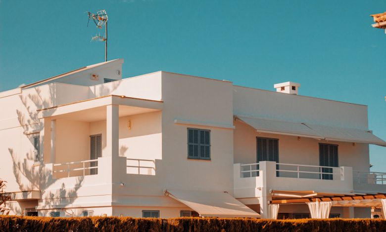 Elegant modern white house with balconies under a clear blue sky in Spain, showcasing minimalistic architecture.