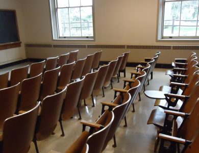An empty university classroom with chairs, desks and a blackboard.