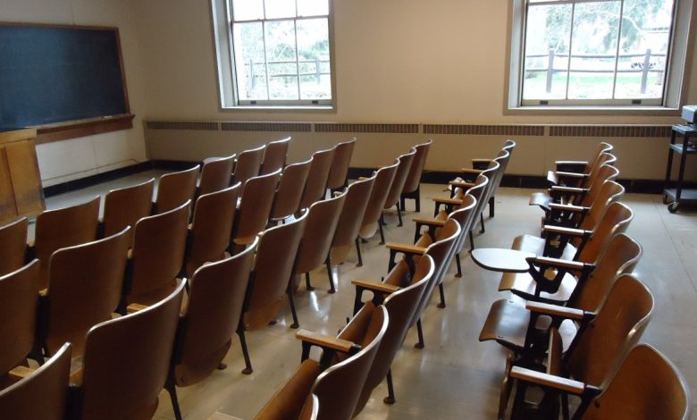 An empty university classroom with chairs, desks and a blackboard.